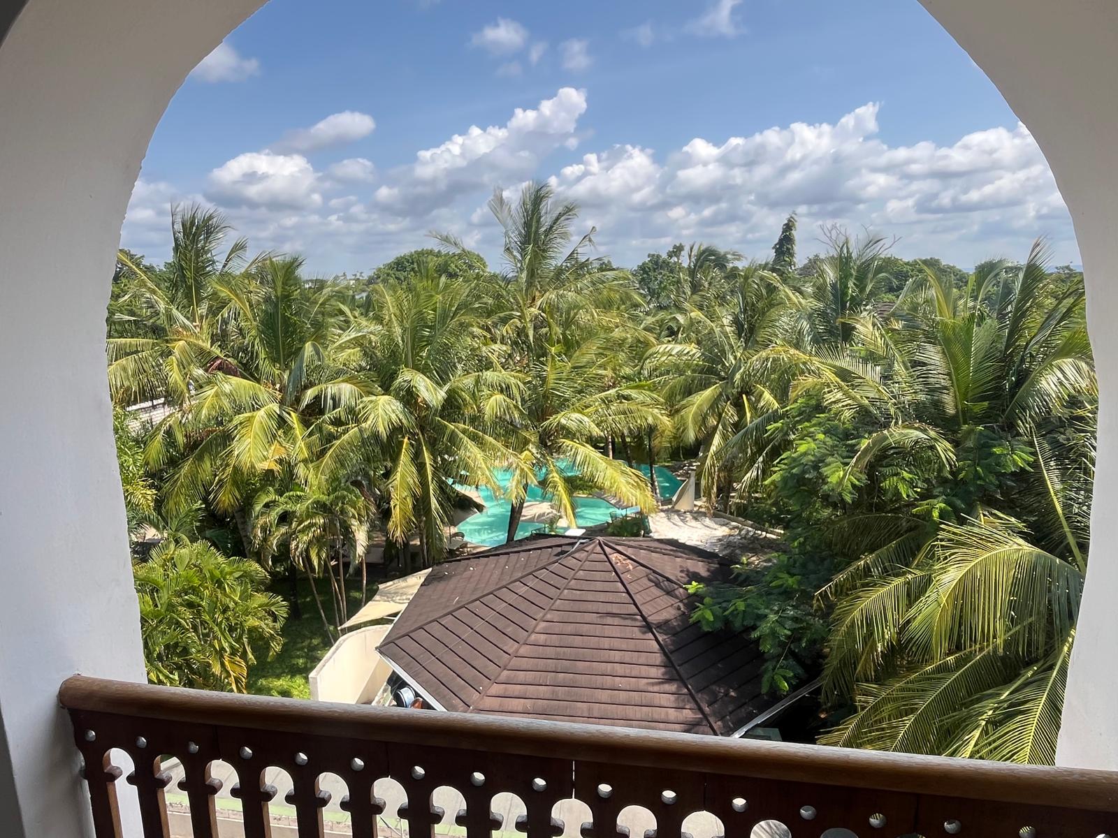 Balcony of the apartment looking down over the swimming pool and coconut palms
