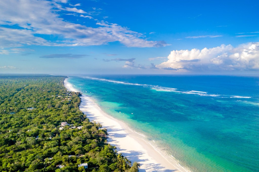Aerial view of the Diani Beach coastline: white sand, the turquoise lagoon and reef, and the coastal forest behind the beach