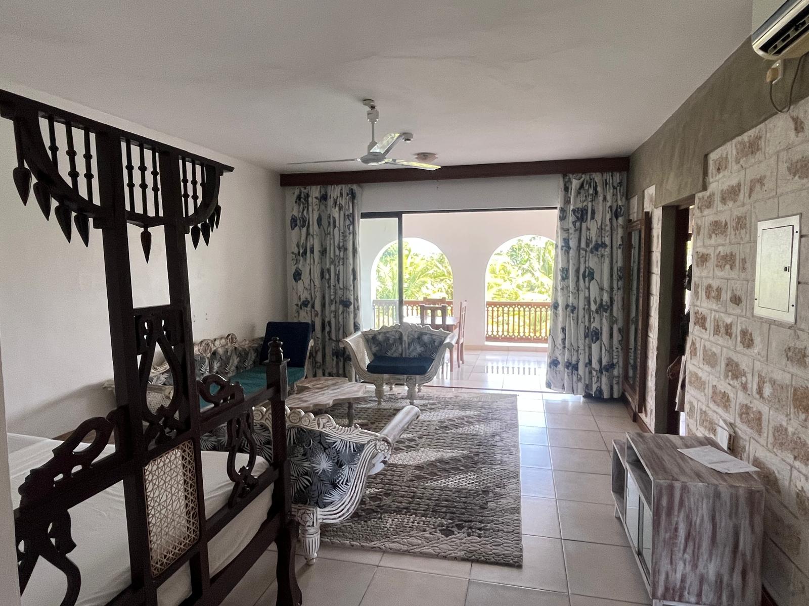 Wide view of the living room showing the seating area and the queen-size bed
